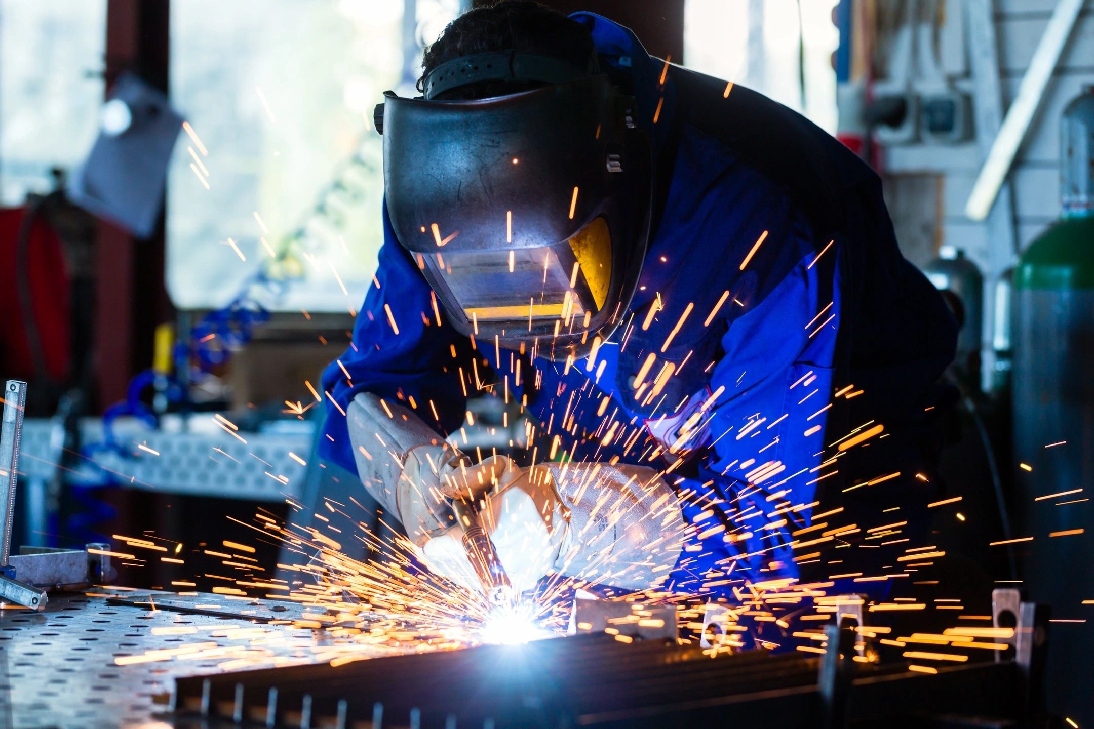 Welder with sparks in industrial workshop